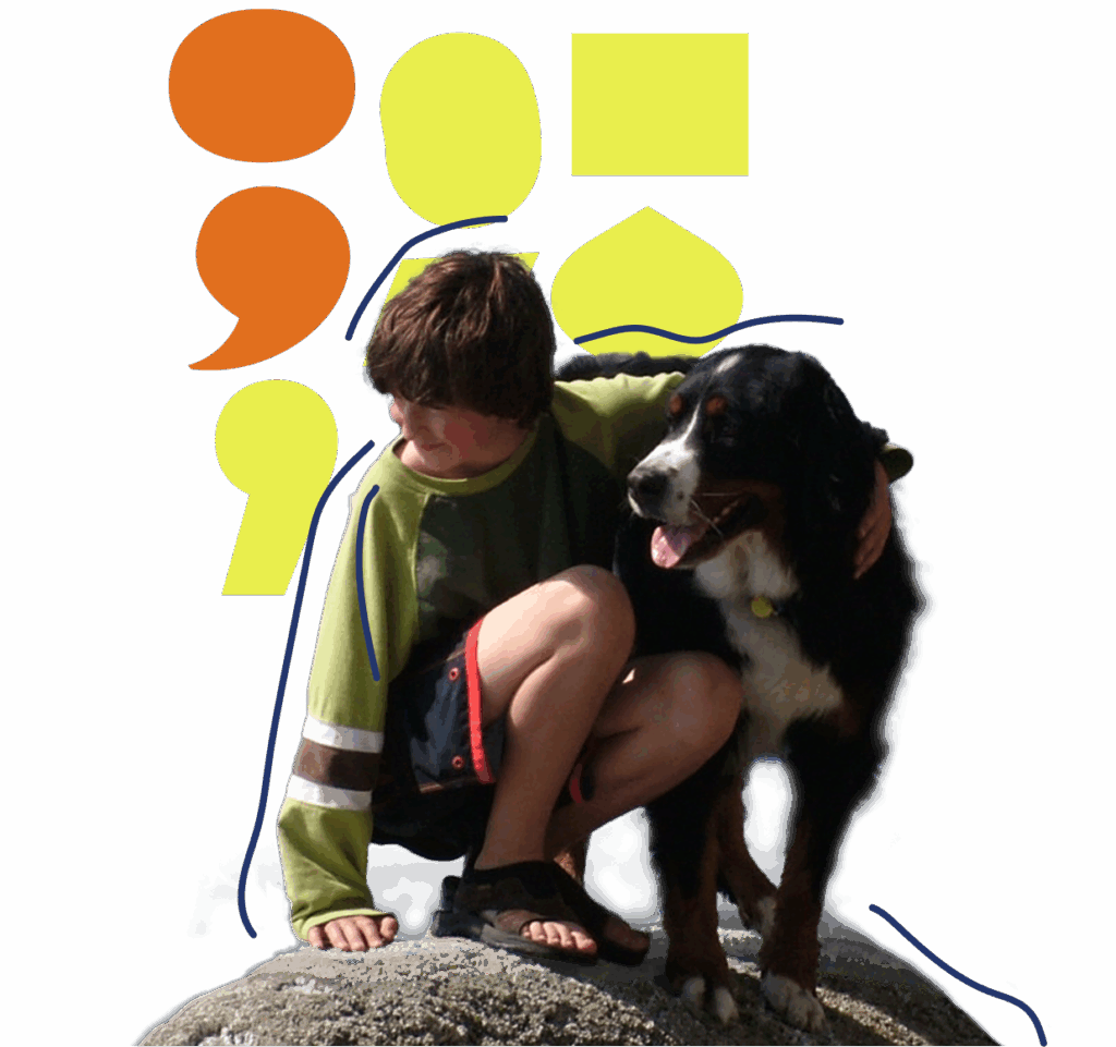 A boy in a green shirt kneels on a rock, hugging a large black, brown, and white dog. Abstract yellow and orange punctuation shapes appear in the background.