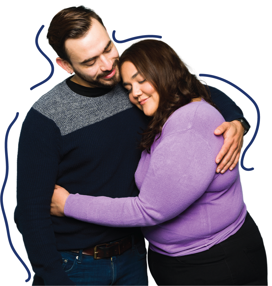 A man and a woman are hugging each other and smiling with their eyes closed. The woman is wearing a purple sweater, and the man is wearing a dark sweater. Blue lines are drawn around them on a white background.